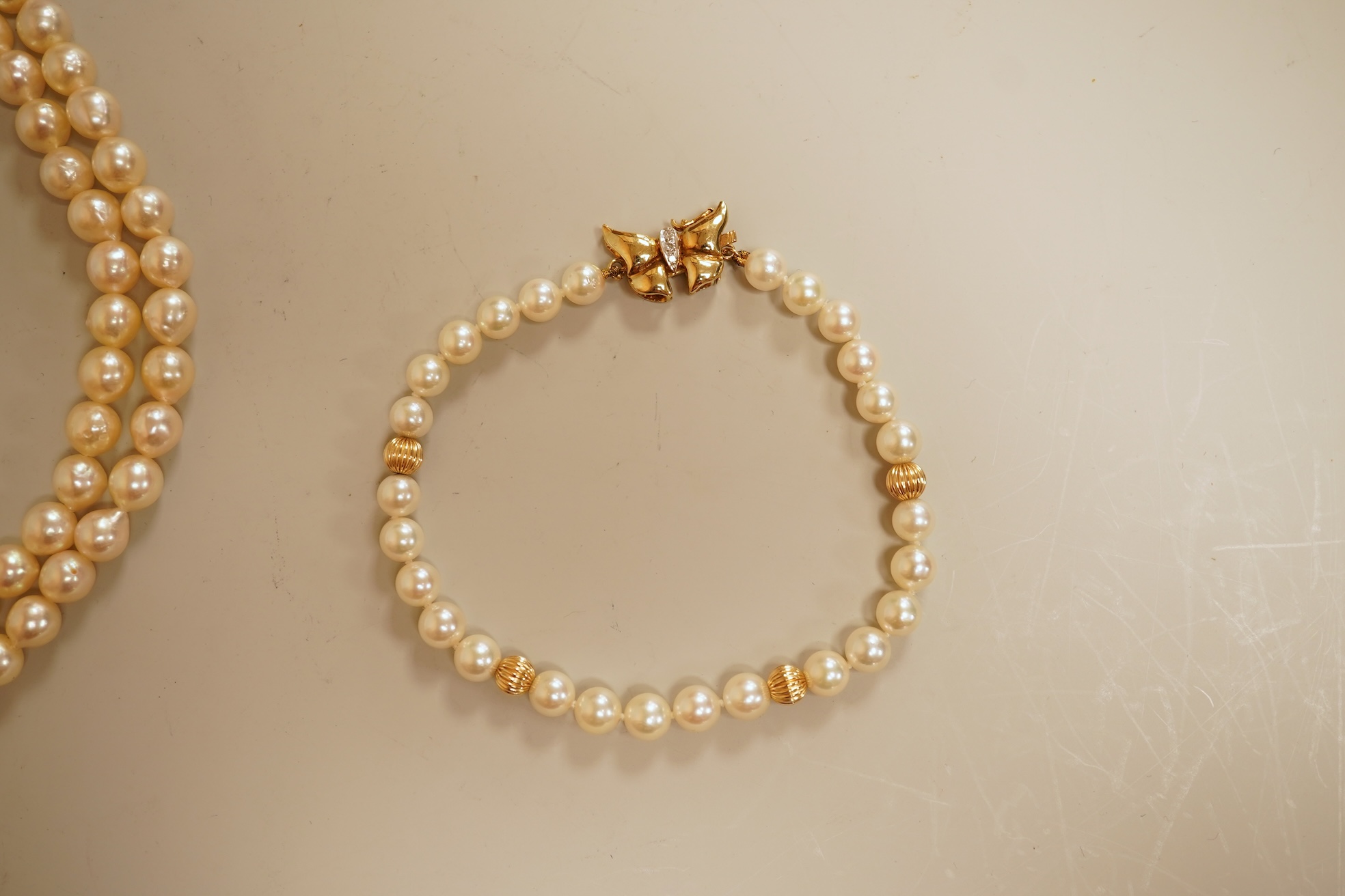 A modern twin strand cultured pearl choker necklace, with an engraved 9ct clasp, approx. 40cm, together with a cultured pearl bracelet, with diamond chip set butterfly shaped 14k clasp, 18cm, with four fluted yellow meta